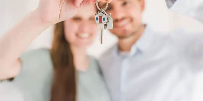 A couple holding out keys to a home toward the camera