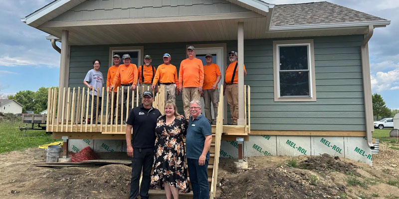 Several Habitat volunteers and staff stand for a photo with the new homeowner at a local build