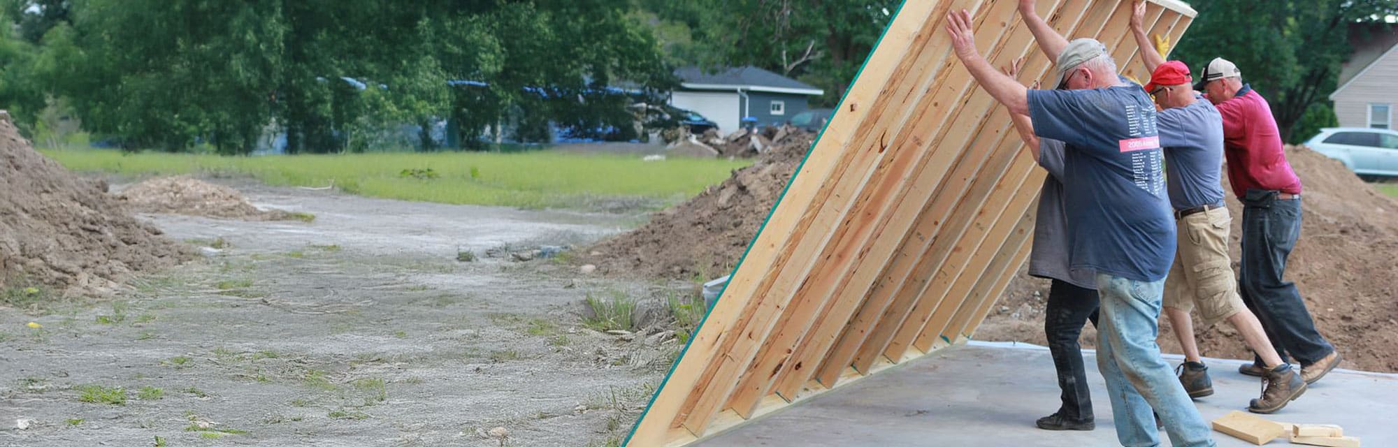 Four Habitat volunteers pushing up a framed wall