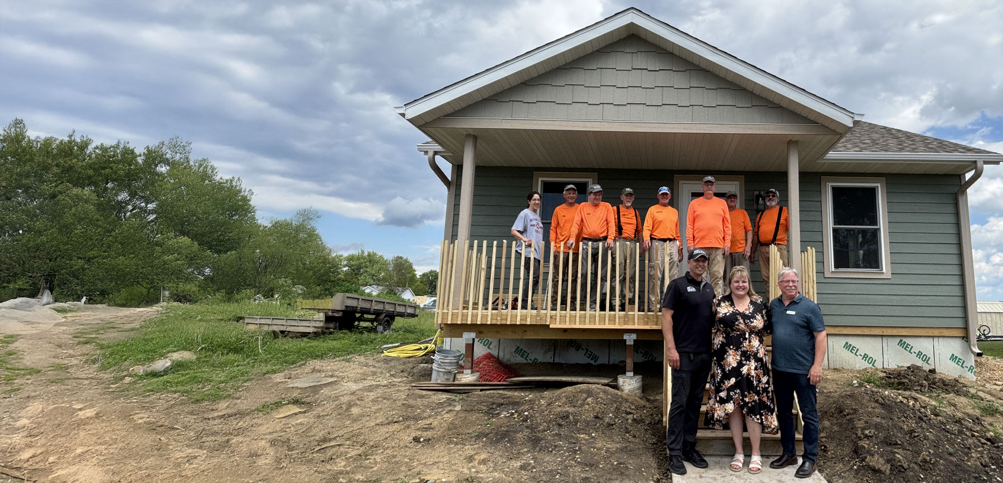Several Habitat volunteers and staff stand for a photo with the new homeowner at a local build