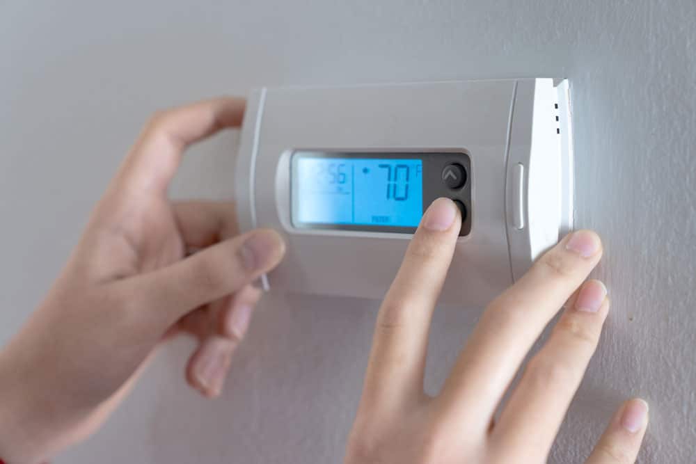 closeup of a woman's hands adjusting a thermostat