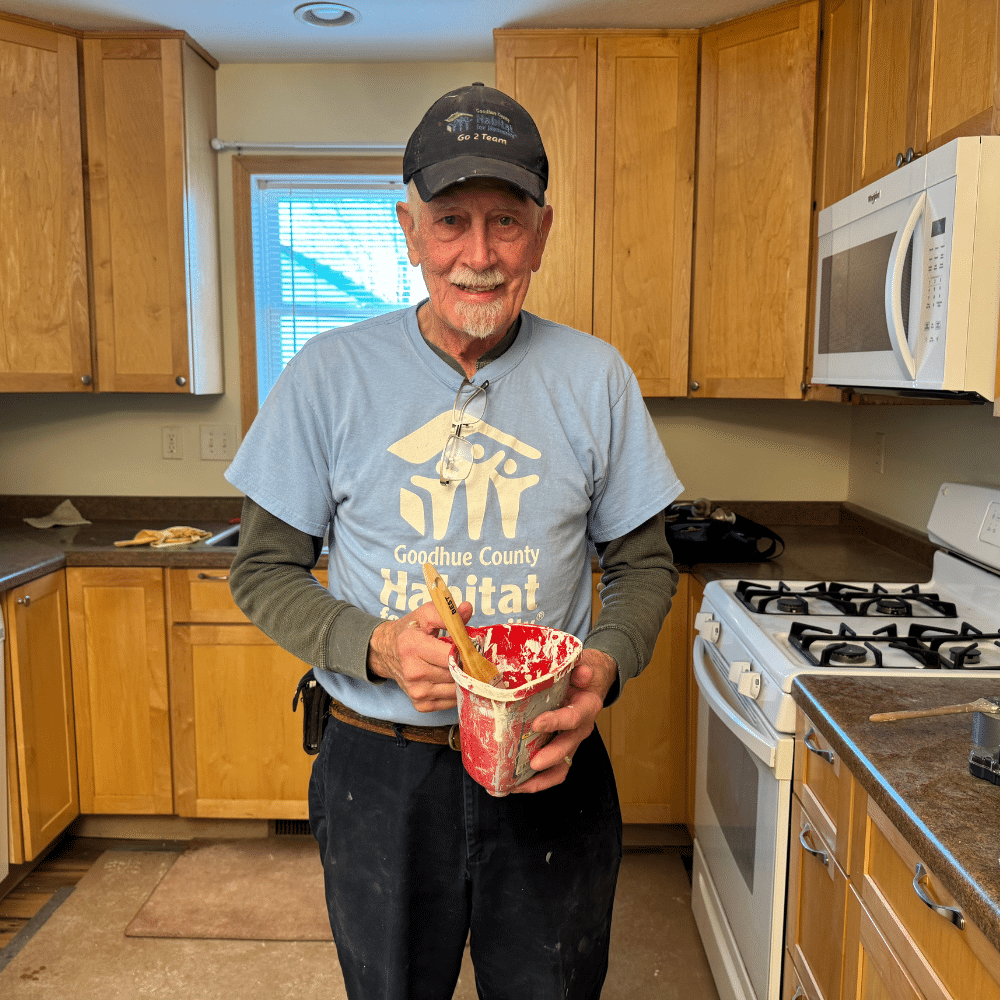 A volunteer holding a paint cup in a Habitat build.
