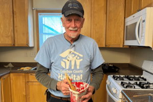 Volunteer Darwin holding a paint can in one of our Habitat builds.
