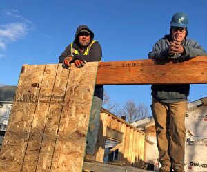 Two Habitat volunteers standing in the framing of a home