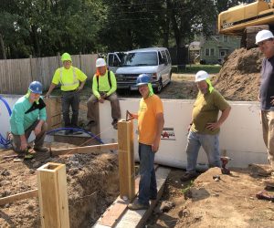 Six men with hard hats standing together at a GCHFH build site