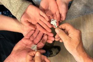 6 hands receiving a house key together