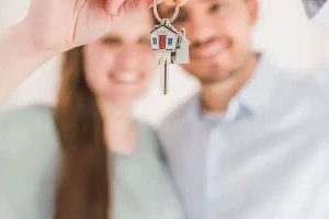 A couple holding out keys to a home toward the camera