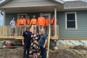 Several Habitat volunteers and staff stand for a photo with the new homeowner at a local build