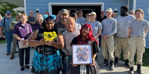 Hope Has a New Address, new homeowners pose with staff and volunteers outside at the home dedication